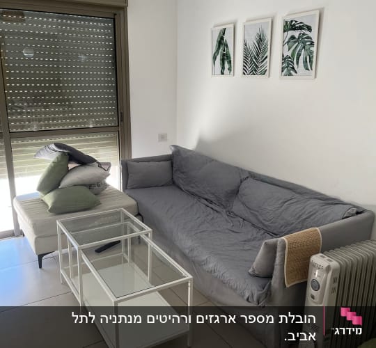 ספה אפורה, שולחן זכוכית, רדיאטור, כריות ירוקות
